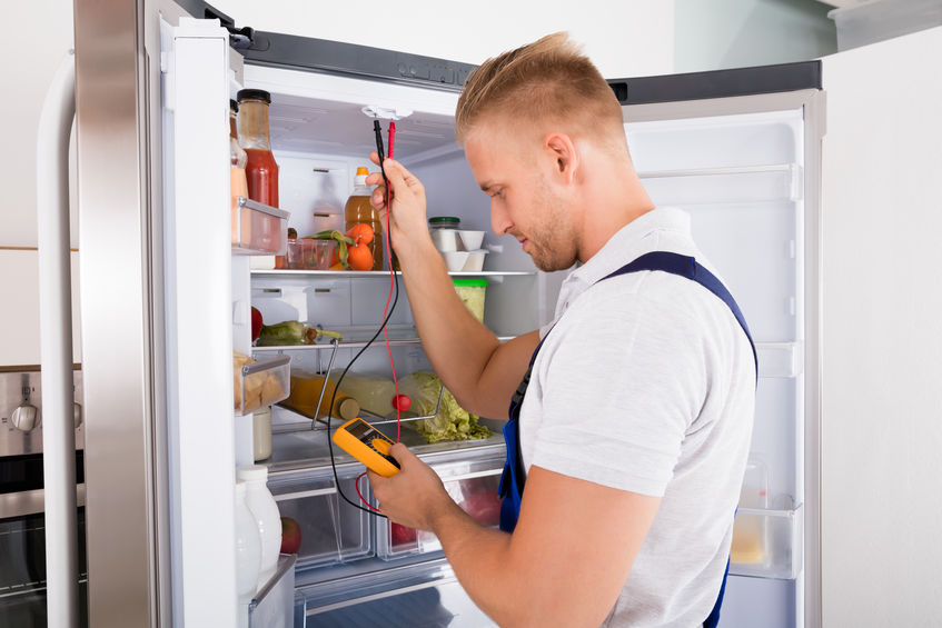70823974 - young repairman checking refrigerator with digital multimeter